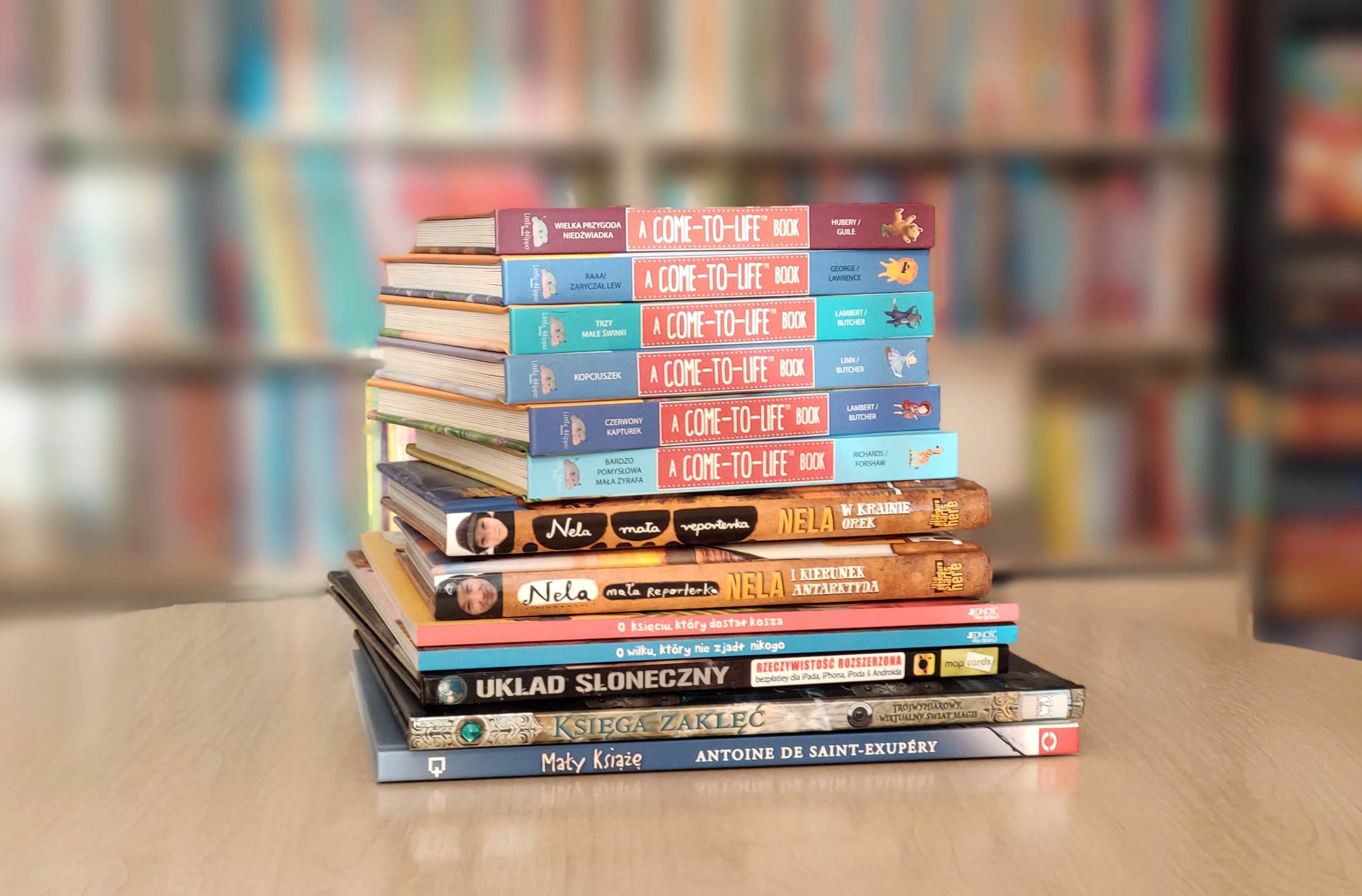 Zdjęcie kolorowe, na stoliku ułożona sterta książek z rozszerzoną rzeczywistością w bezpłatnej aplikacji