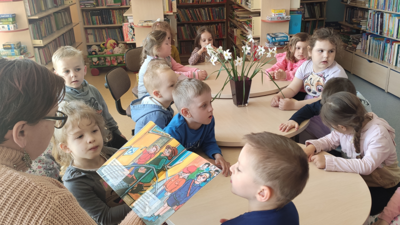Zdjęcie kolorowe, przedszkolaki z życzeniami z okazji dnia bibliotekarza w bibliotece
