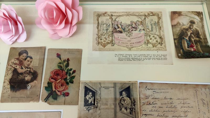Zdjęcie kolorowe, fragment wystawy kartek pocztowych w holu biblioteki
